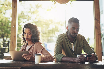 Buy stock photo Cropped shot of two young people using their wireless devices in a coffee shop