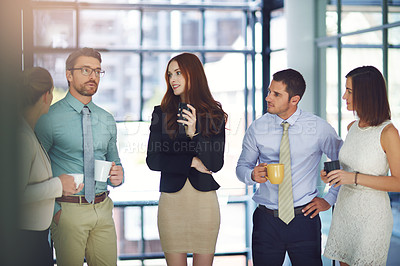 Buy stock photo Shot of colleagues having a discussion and drinking coffee in a modern office