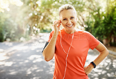 Buy stock photo Fit female athlete going for morning run, adjusting earphones, listening to music. Happy, healthy sports woman smiling, about to do cardio wellness exercise or take endurance training workout break.