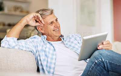 Buy stock photo Relaxed, happy and carefree man relaxing on couch calm, smiling, happy and joyful while holding his tablet in his hands. Casual male enjoying his leisure at home while sitting on the sofa.