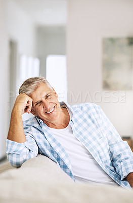 Buy stock photo Casual, relaxed and happy mature man smiling indoors on his couch at home on a relaxing day. Portrait of a handsome senior male sitting on his comfortable sofa enjoying his time alone at his house