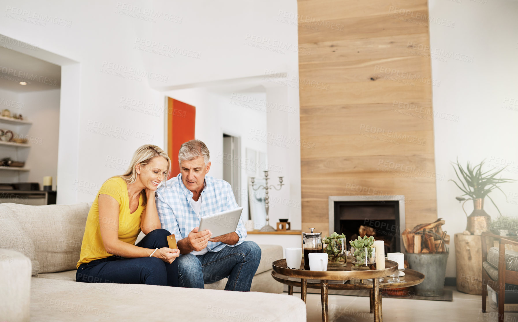 Buy stock photo Cropped shot of a mature couple using a digital tablet while relaxing at home