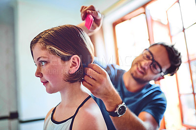 Buy stock photo Shot of a father combing his little daughter's hair at home