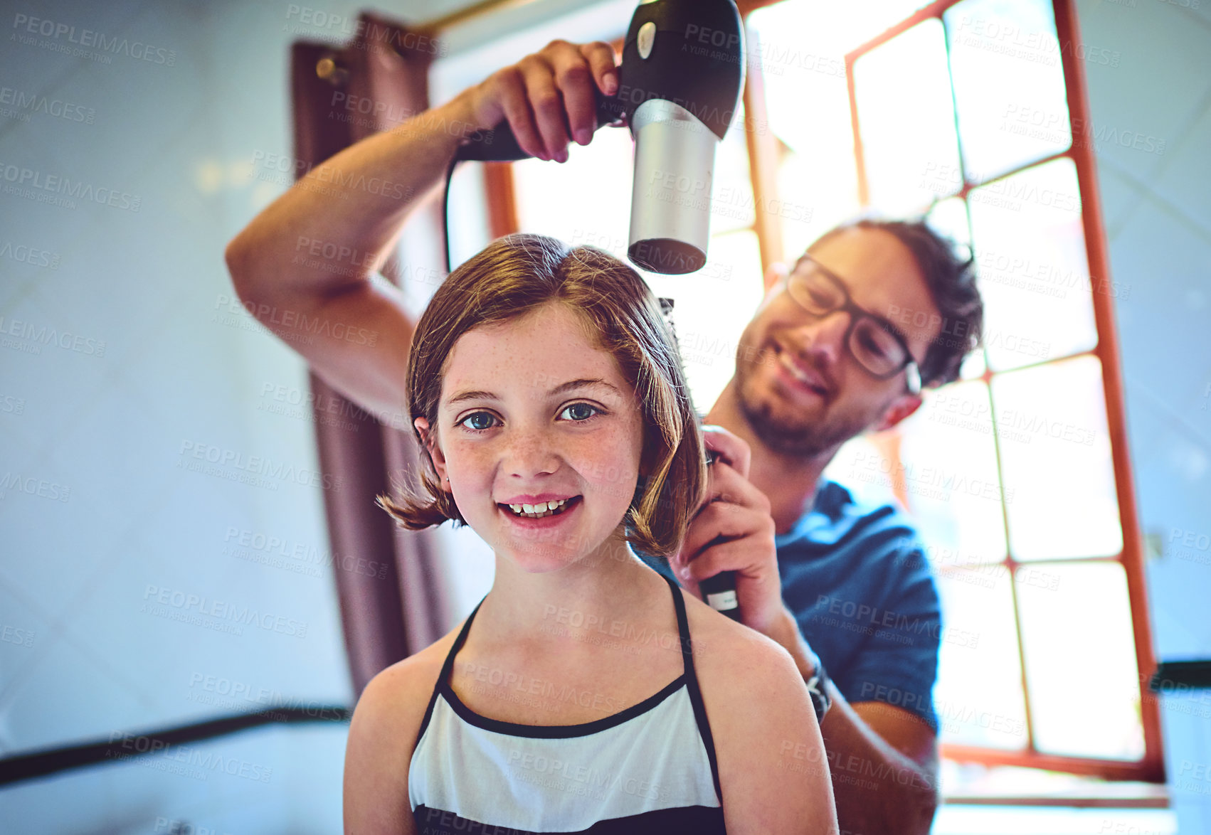 Buy stock photo Shot of a father blowdrying his little daughter's hair at home