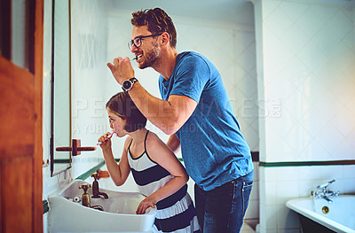 Buy stock photo Shot of a father and his little daughter brushing their teeth together at home