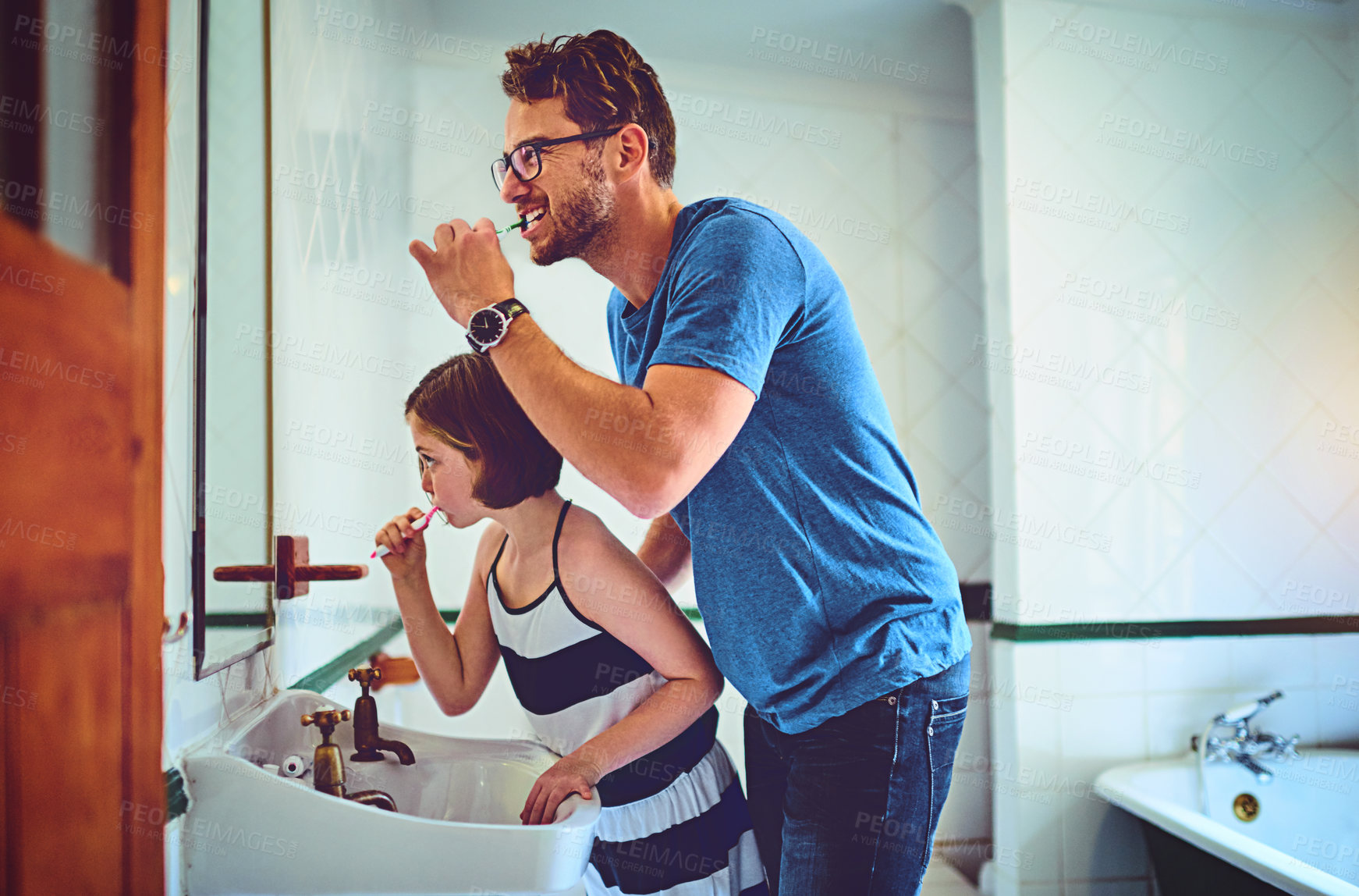 Buy stock photo Shot of a father and his little daughter brushing their teeth together at home
