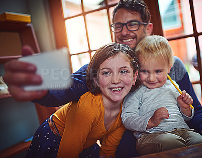 Buy stock photo Shot of a father taking a selfie with his little son and daughter at home