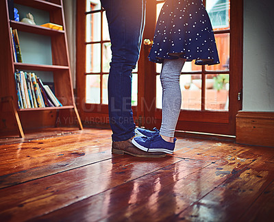 Buy stock photo Shot of a little girl standing on her father's feet at home