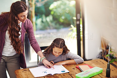 Buy stock photo Cropped shot of a young girl doing homework with her mother inside