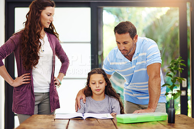 Buy stock photo Cropped shot of a young girl doing homework with her parents inside