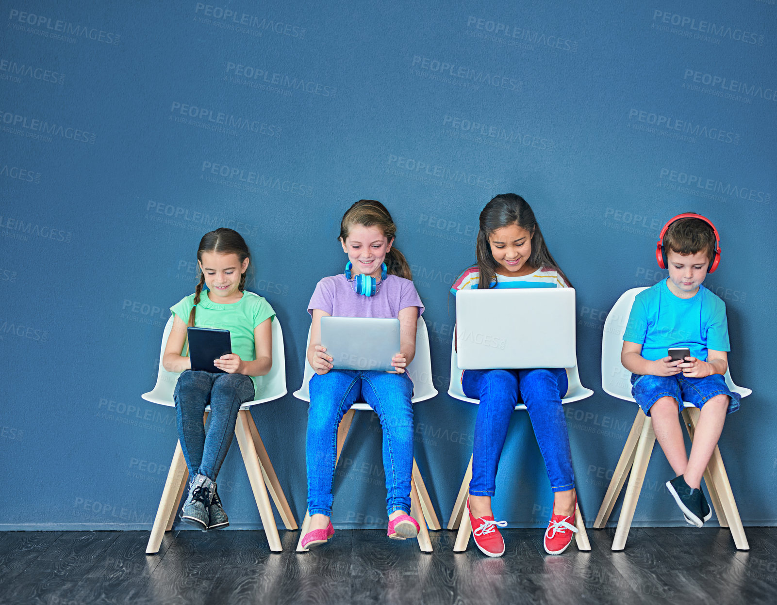 Buy stock photo Children with a laptop, tablet and phone for learning and education while online for research on internet. Kids or students against a blue mockup wall with technology on chairs in a waiting room