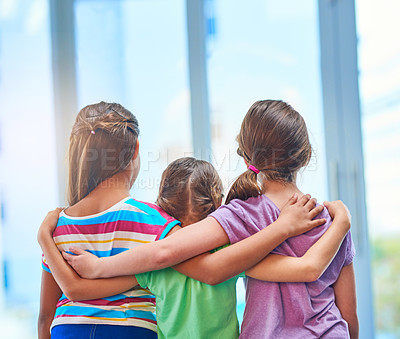 Buy stock photo Rearview shot of three young girls embracing each other