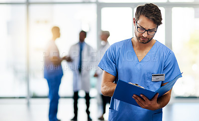 Buy stock photo Doctor, healthcare professional and medical worker reading, holding and looking at health information and records in a hospital. Practitioner with a clinic file and colleagues in the background