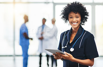 Buy stock photo Portrait of a young doctor using a digital tablet with her colleagues in the background