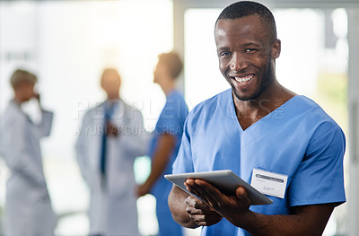 Buy stock photo Portrait of a young doctor using a digital tablet with his colleagues in the background