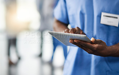 Buy stock photo Cropped shot of a doctor using a digital tablet with his colleagues in the background