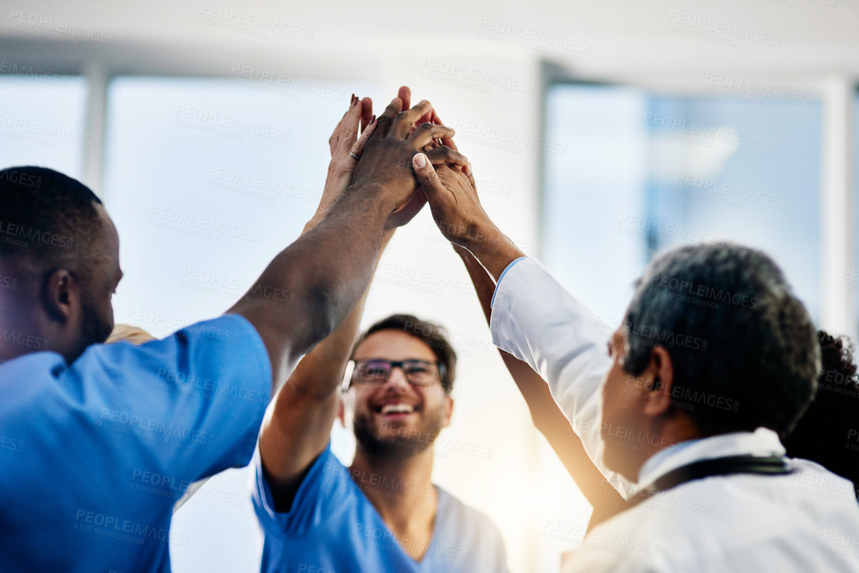Buy stock photo Doctors celebrating medical success after working together as a team and give each other motivating a high five as a group in a hospital. Healthcare workers joining hands in a huddle showing teamwork