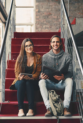 Buy stock photo Full length portrait of two young university students studying while sitting on a staircase on campus