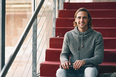 Buy stock photo Cropped portrait of a handsome young university student studying while sitting on a staircase on campus