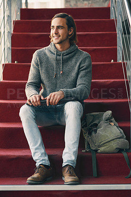 Buy stock photo Full length shot of a handsome young university student studying while sitting on a staircase on campus