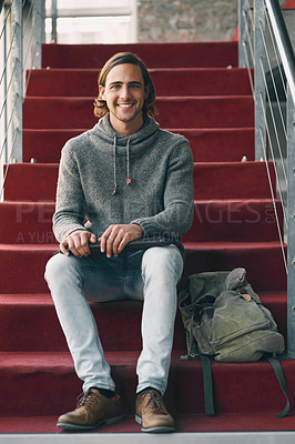 Buy stock photo Full length portrait of a handsome young university student studying while sitting on a staircase on campus