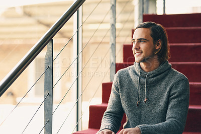 Buy stock photo Cropped shot of a handsome young university student studying while sitting on a staircase on campus