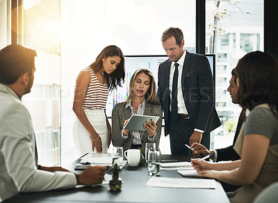 Buy stock photo Shot of businesspeople using a digital tablet in a boardroom meeting