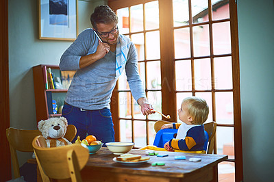 Buy stock photo Cropped shot of a single father on a call while feeding his son at home