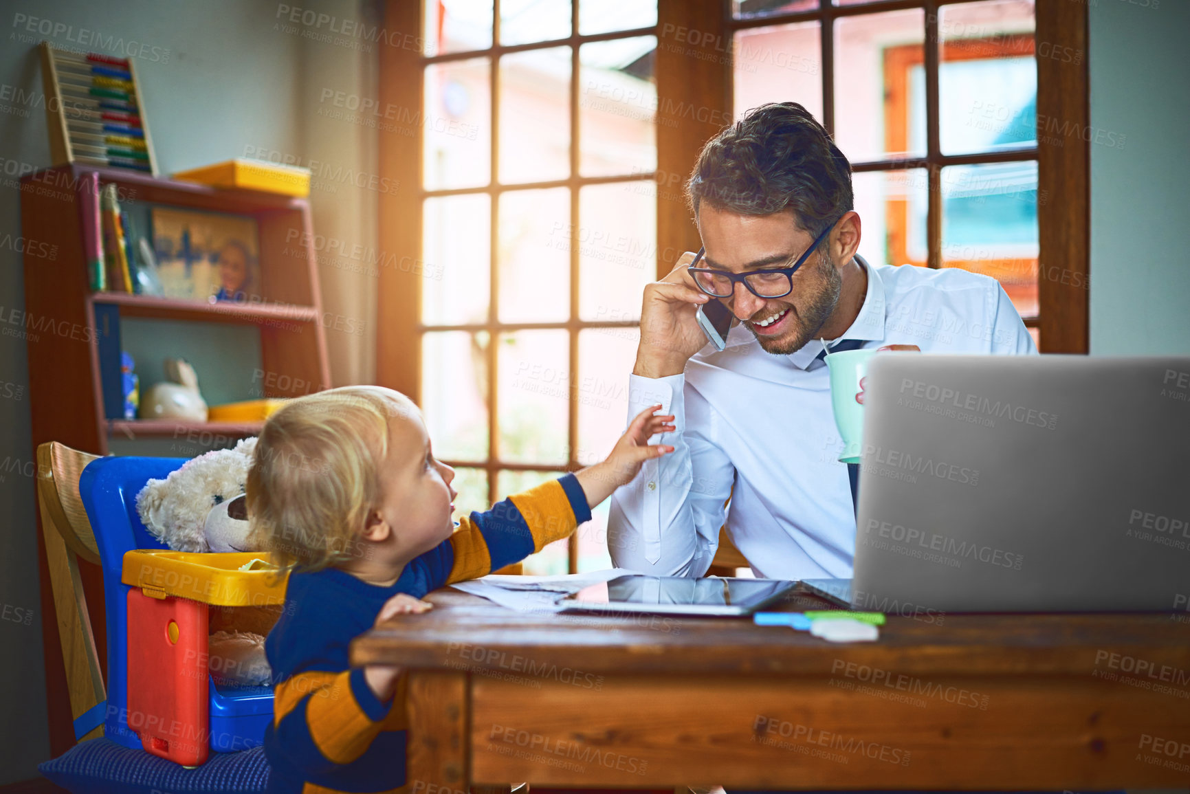 Buy stock photo Shot of a single father taking a call from his son at home