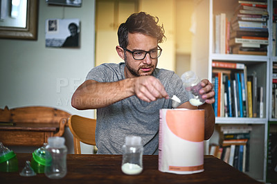 Buy stock photo Cropped shot of a single father preparing a bottle for his baby at home