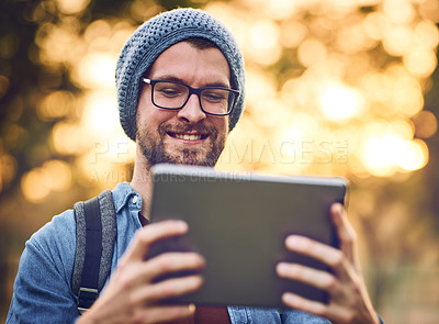 Buy stock photo Cropped shot of a handsome young man using a tablet outdoors