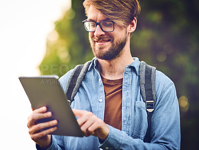 Buy stock photo Cropped shot of a handsome young man using a tablet outdoors
