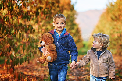 Buy stock photo Cropped shot of an adorable little boy walking hand in hand with his older brother outdoors during autumn