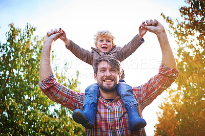 Buy stock photo Low angle portrait of a handsome young man piggybacking his son outside during autumn