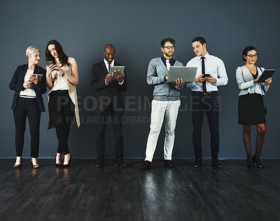 Buy stock photo Studio shot of a group of businesspeople using various digital devices against a grey background