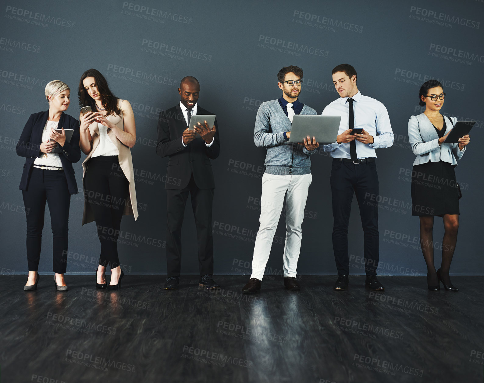 Buy stock photo Studio shot of a group of businesspeople using various digital devices against a grey background