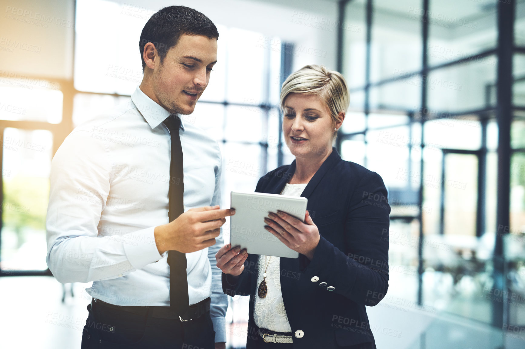 Buy stock photo Shot of two businesspeople working on a digital tablet in an office