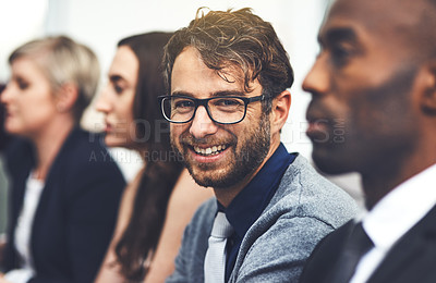 Buy stock photo Portrait of a young businessman sitting alongside his colleagues in an office