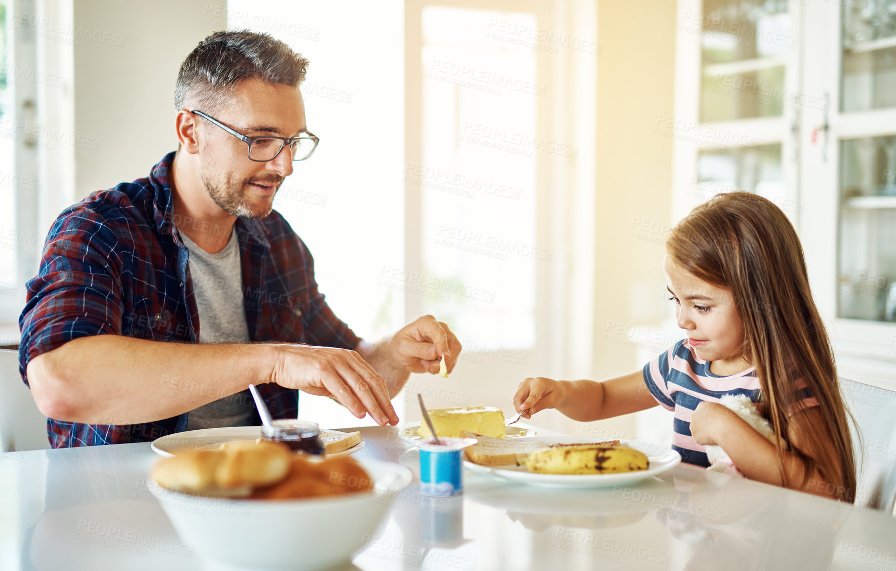 Buy stock photo Breakfast, bread and daughter with dad, table or morning in kitchen, butter and dining in home. Healthy, father and food of family, child and man in house, eating and bonding with love together