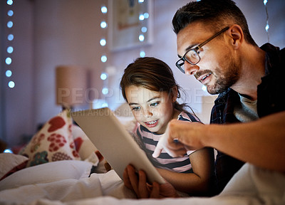 Buy stock photo Cropped shot of a father reading his young daughter a bedtime story on a tablet