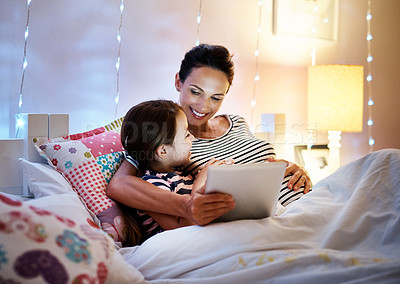 Buy stock photo Shot of an attractive young pregnant woman reading her daughter a bedtime story on a tablet