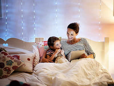 Buy stock photo Shot of an attractive young pregnant woman reading her daughter a bedtime story on a tablet