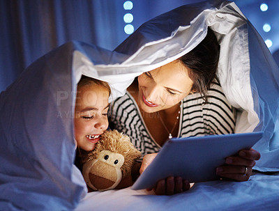 Buy stock photo Cropped shot of an attractive young pregnant woman reading her daughter a bedtime story on a tablet