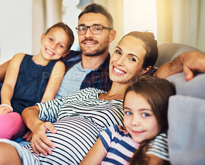 Buy stock photo Cropped portrait of a happy young family of four relaxing on the sofa in their home