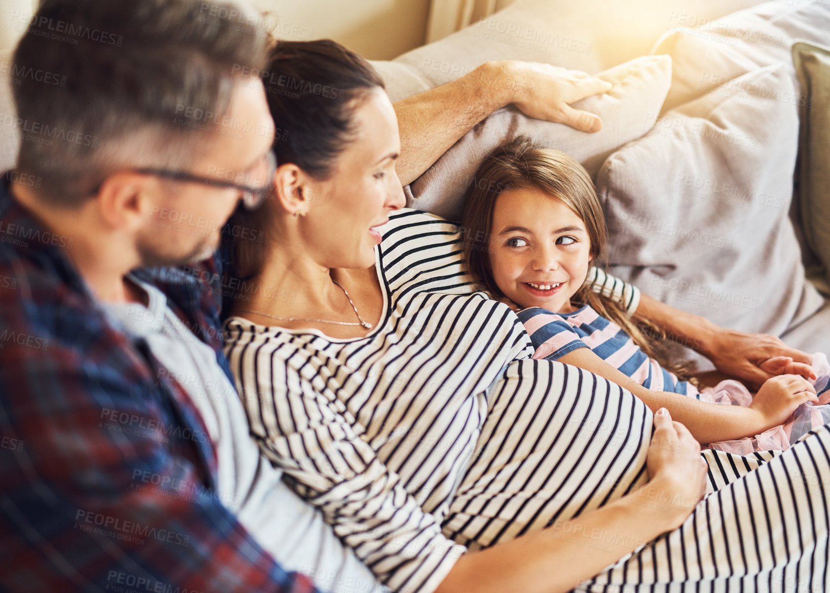 Buy stock photo High angle shot of a happy young family of three relaxing on the sofa in their home