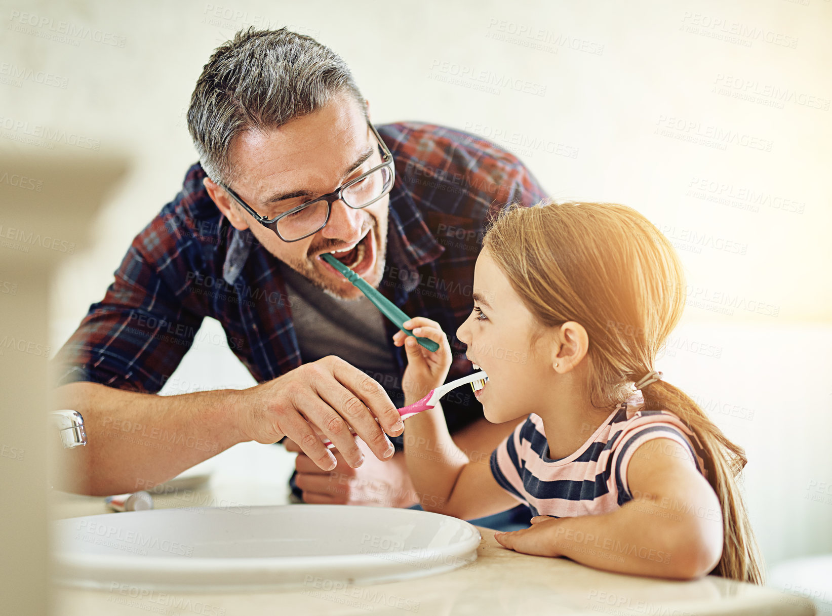 Buy stock photo Cropped shot of a handsome mature man and his daughter brushing their teeth in the bathroom