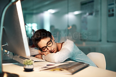 Buy stock photo Shot of a young businesswoman sleeping on her desk at the office