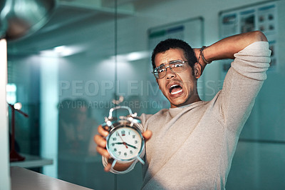 Buy stock photo Shot of a young businessman holding a clock worrying about his deadline at the office