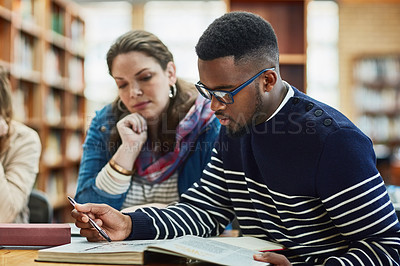 Buy stock photo Shot of a group of university students working in the library at campus