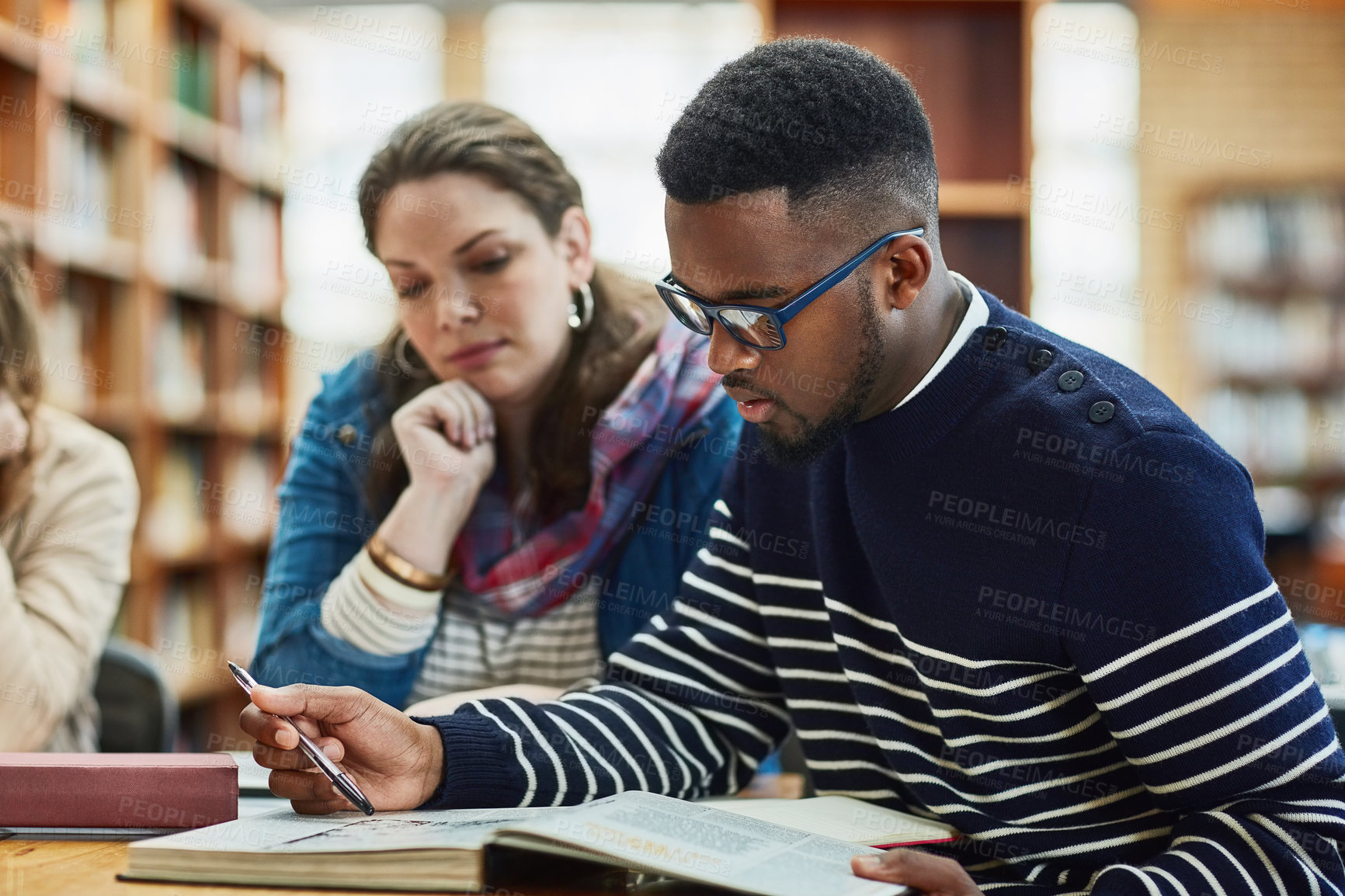 Buy stock photo Library, people and studying with book, reading and desk for exam, woman and man in campus of college. Students, friends and teamwork for test, information and table with research and together